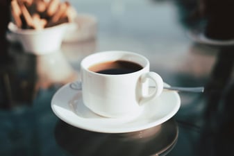 A cup of long black coffee with crema on a white ceramic saucer