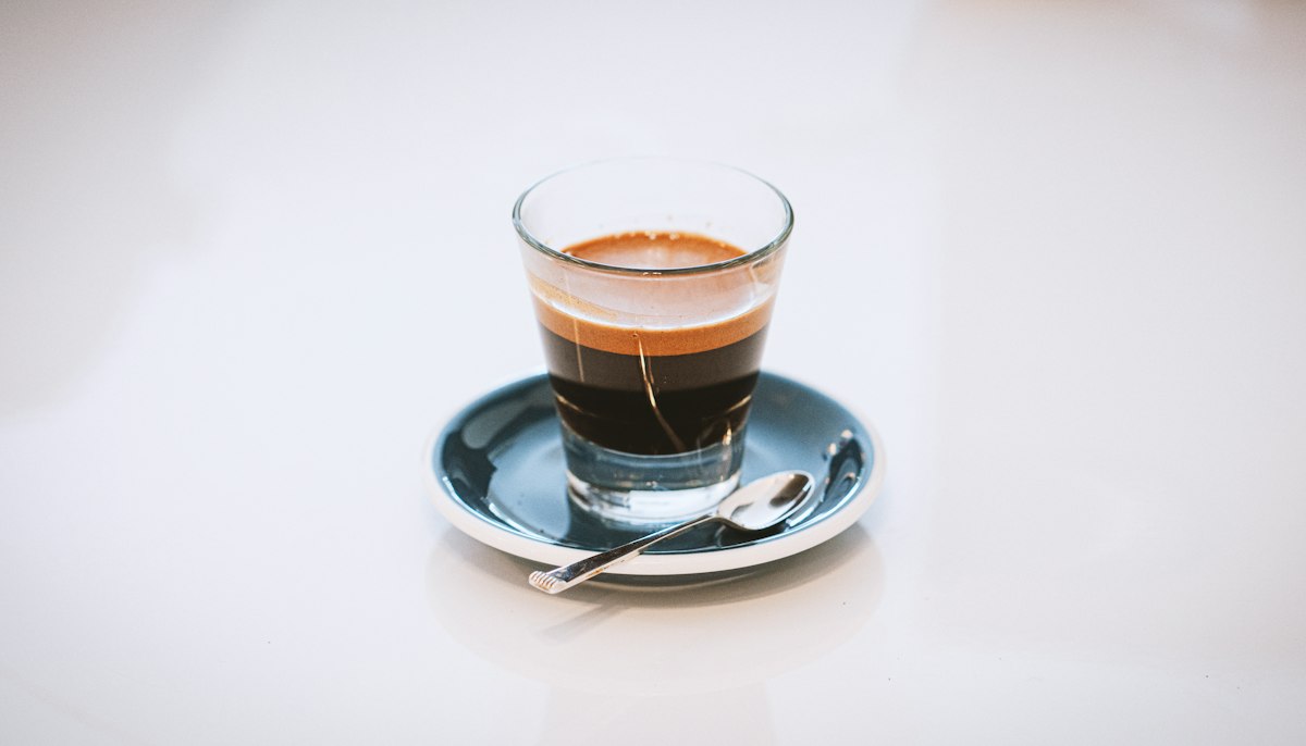A short ristretto shot with thick crema in a small glass on a saucer