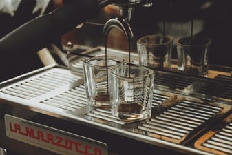Espresso pouring from a La Marzocco espresso machine group head into a small glass