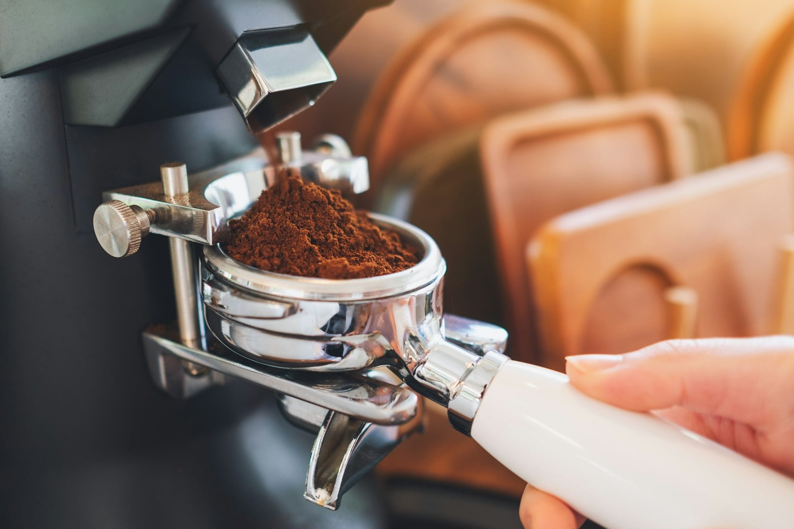 Freshly ground coffee falling into the basket of an espresso machine portafilter
